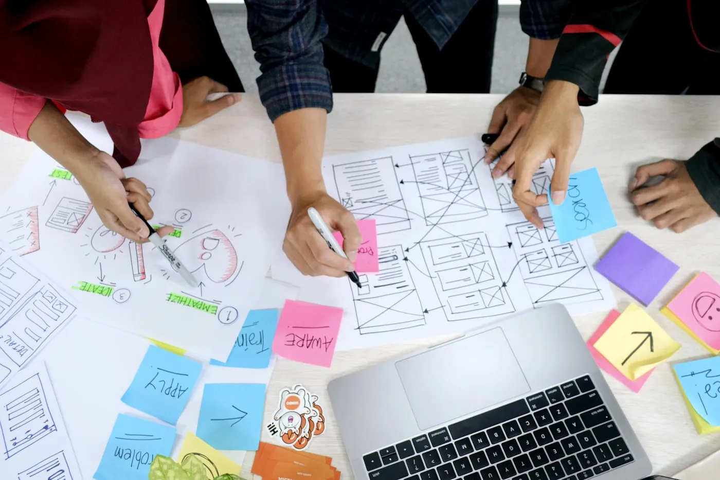 A team sketching website wireframes and user flows on paper during a planning session