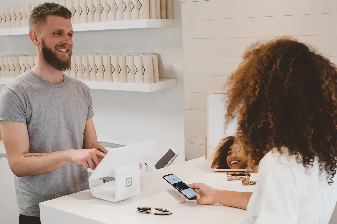 A customer paying by phone at a retail checkout counter using a point-of-sale tablet